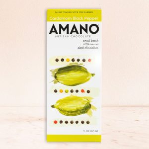 Amano artisan chocolate bar featuring cardamom and black pepper is set against a light background. The packaging showcases artistic green cardamom illustrations.