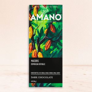 Bar of Amano Artisan Chocolate with vibrant green and orange cocoa pod design. Labeled "Macoris Dominican Republic," highlights dark, single-origin chocolate.