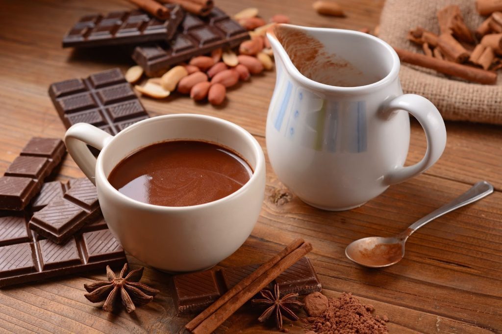 A cozy cup of hot chocolate with cocoa and spices displayed on a wooden table, inviting warmth and comfort.