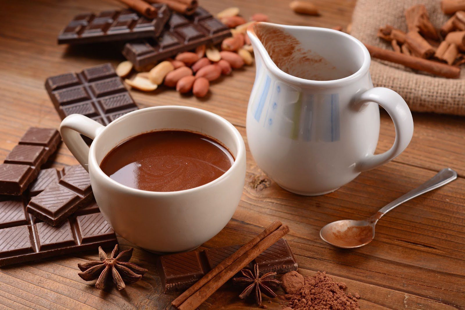 A cozy cup of hot chocolate with cocoa and spices displayed on a wooden table, inviting warmth and comfort.