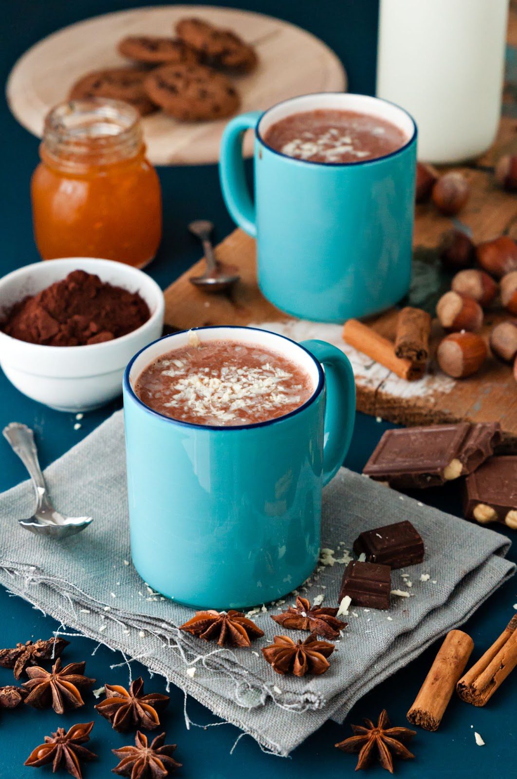 A cup of hot chocolate with nuts and spices, set against a blue table background.