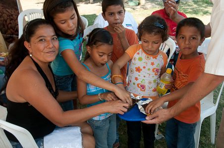 A lively group of children and adults participate in a chocolate-making session, sharing smiles and learning together.