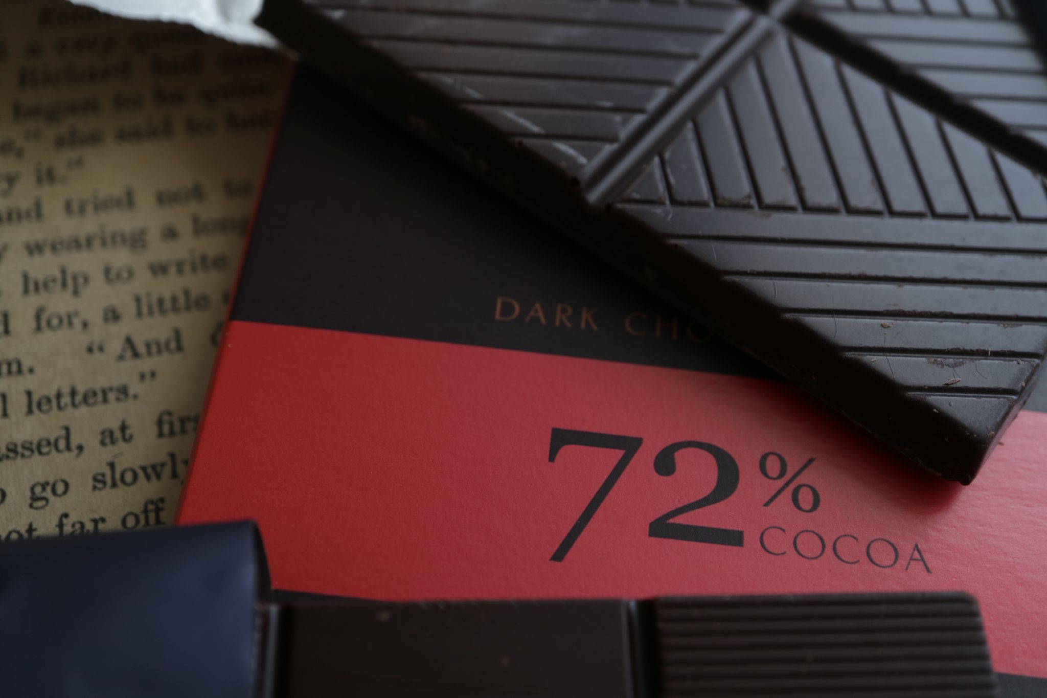 Close-up of a 72% cocoa dark chocolate bar lying over its red packaging.